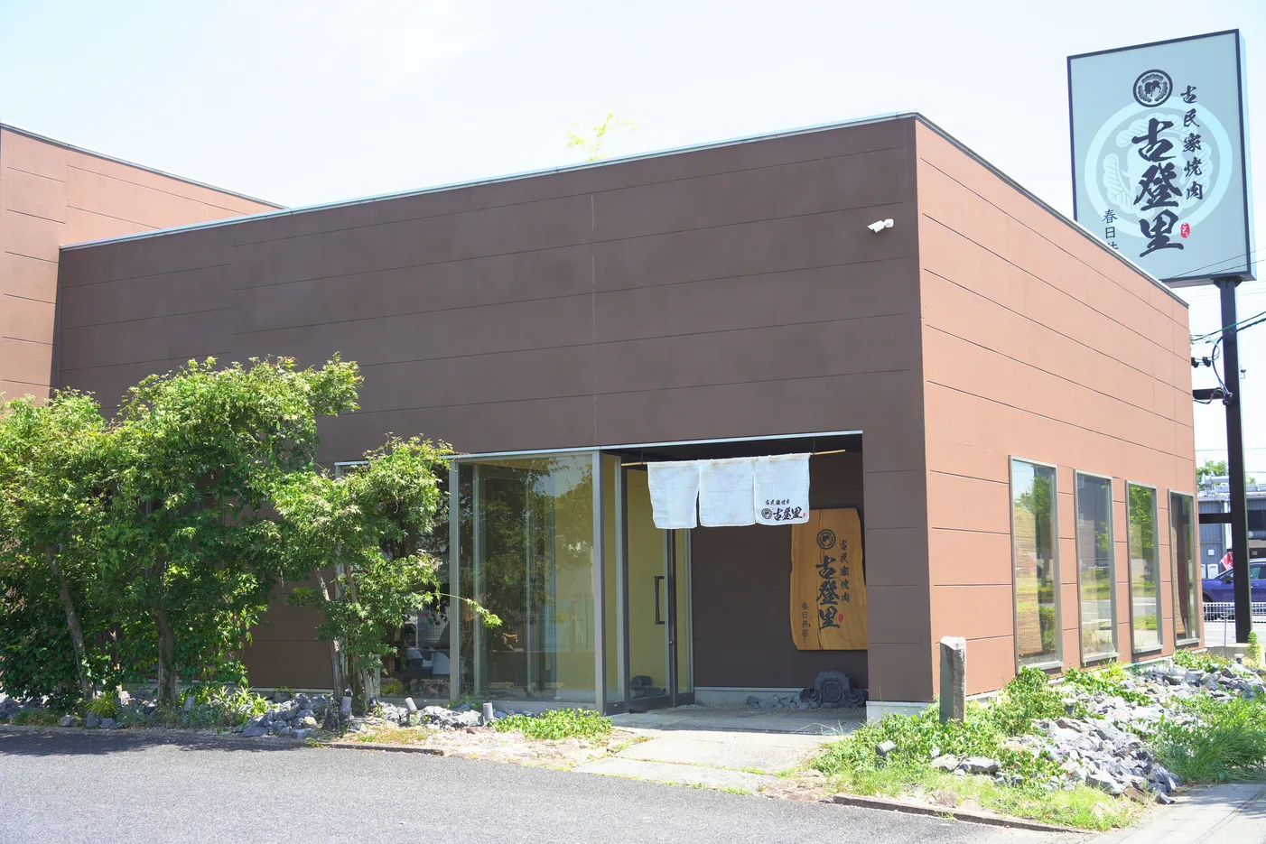看板が立つ、茶色い外壁の店舗外観