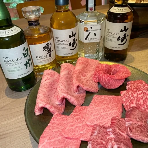 ウイスキーなどのボトルと、皿に盛った牛肉