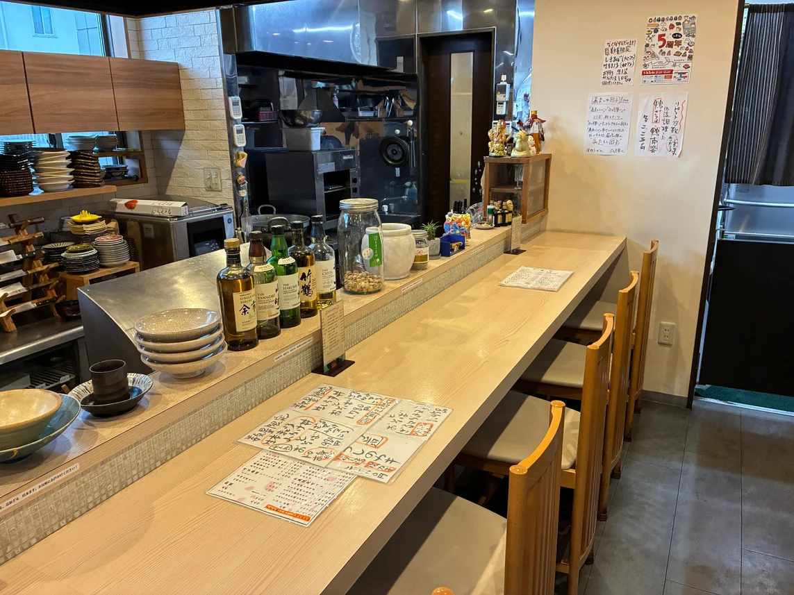 酒瓶が並ぶ、木のカウンター席