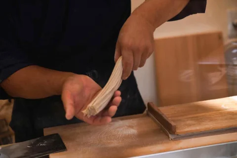 打ち台の前で、切った蕎麦を手に持つ職人