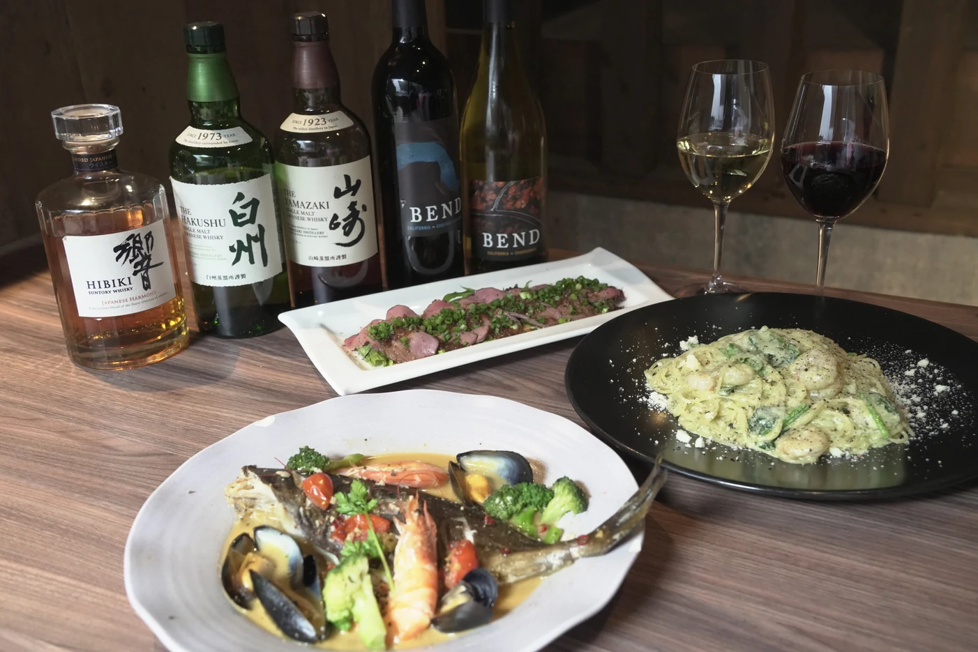 魚料理、ローストビーフ、パスタとワインが並ぶテーブル